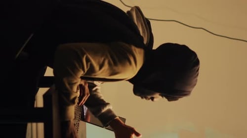 Hooded Figures Working with Computers at Night