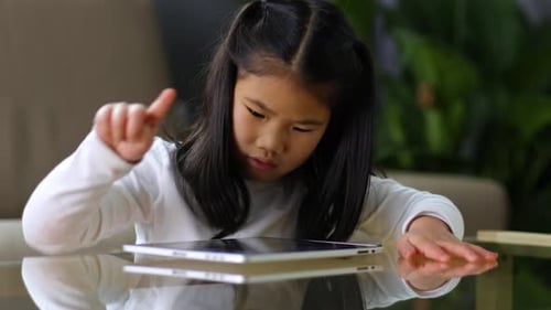 Girl using Tablet at Glass Table Indoors