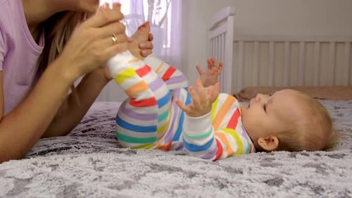 Mother Playing with Infant on Bed at Home