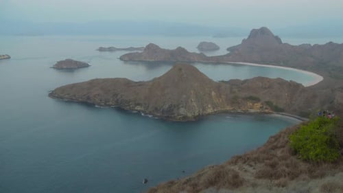 Stunning view from Padar Island of Pink Beach and mountains on a misty day during twilight in Indone