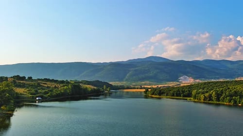 Lake with Clear Water and Stone Shore in Spruce Forest with Fir Trees Against a Daytime Sky