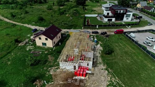 Drone shot circling a unfinished house roof construction area, in a neighborhood