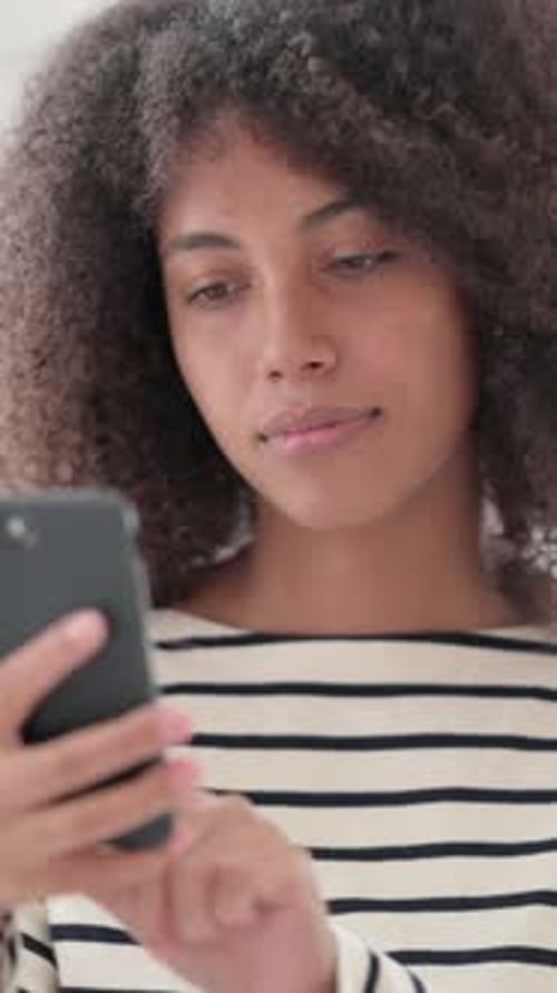 Woman Using Mobile Phone Indoors with Neutral Expression