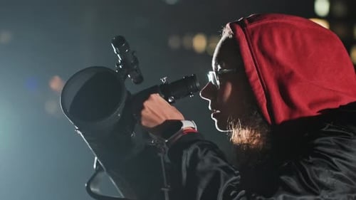 Woman Looking Through Telescope at Night in Urban Setting