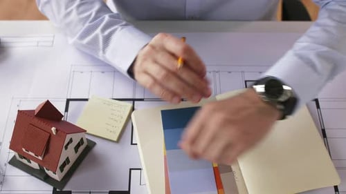Building, Construction and Time Concept - Male Architect with Notebook, Blueprint Of