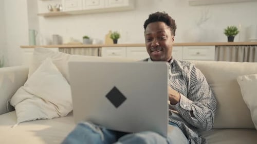 Smiling Young Adult Uses Laptop at Home