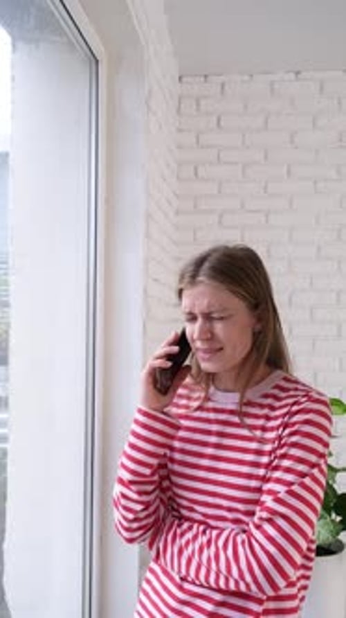 Young Woman Talking on Phone by Window Indoors