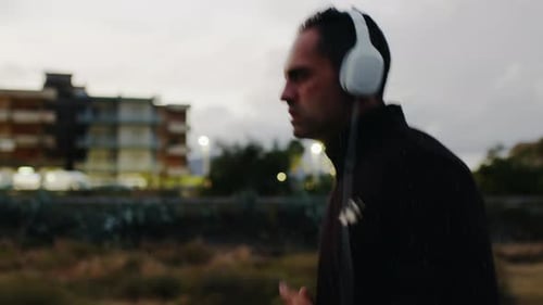 Man Jogging Outdoors with Headphones in Urban Setting