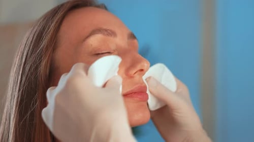 Beautician Wiping Woman Face with Cotton Pads at Beauty Clinic