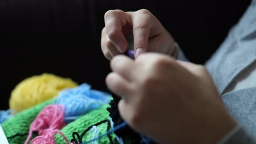 Hands Crocheting Blue Yarn with Colorful Wool