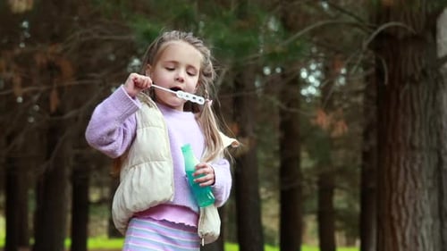 Girl Blowing Bubbles in a Forest Area