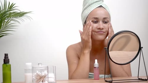 Woman Applies Lotion to Face in Mirror