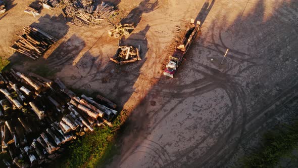 Logging operation at sunset with trucks and stacks of timber in a rural ...