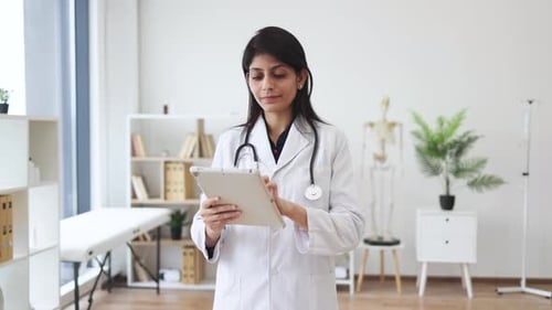 Therapist holding tablet while posing in doctor's office