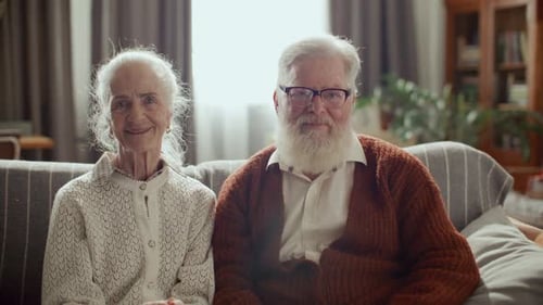 Elderly Couple Smiling Together on Couch at Home