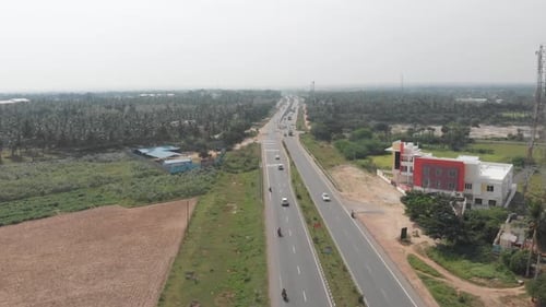 Beautiful shot of cars and trucks driving down a highway in a rural area of India during a sunny day
