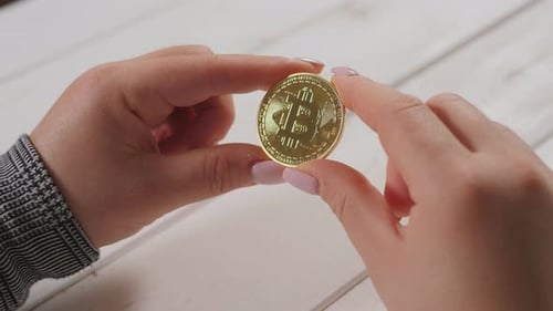 Woman Holds Bitcoin Cryptocurrency in her Fingers