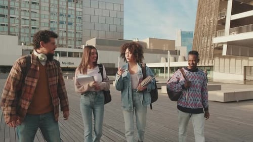 Classmates students walk down the street talking and laughing together