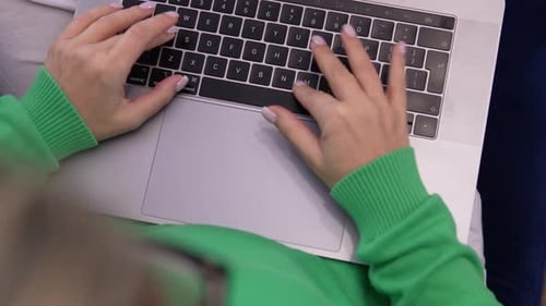Close-up of hands typing on a laptop keyboard in a modern workspace. Focus on productivity and remot
