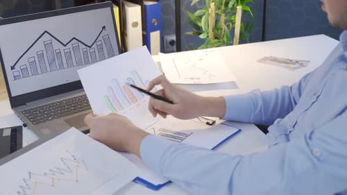 Reviewing Data at White Office Desk with Laptop