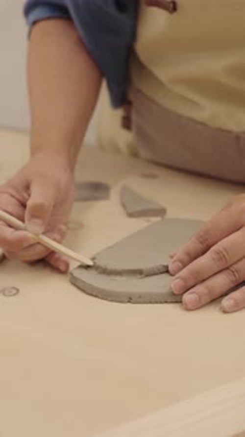 Ceramist Using Wooden Tool Shaping Clay in Workshop