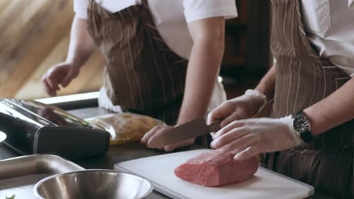Chef Preparing To Cut A Piece Of Veal In Interior Kitchen With Soft Day Lighting. Close Up Shot O...