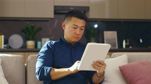 Man Using Tablet on Gray Couch at Home