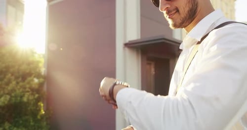 4k video footage of a handsome young businessman checking the rime on his watch in the city