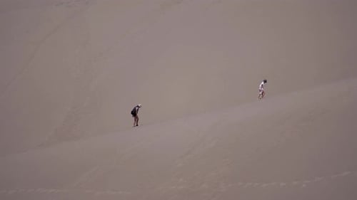 People Trekking Up Desert Sand Dunes