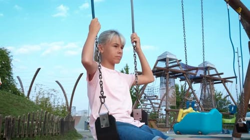 Emotional Teen Riding a Swing on Playground