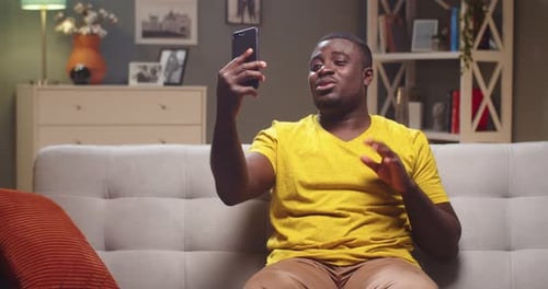 Man Video Calling on Phone While Relaxing at Home