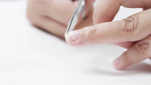 Close Up of Woman Carefully Removing Hangnail with Tweezers Focusing on Precise Nail Grooming and
