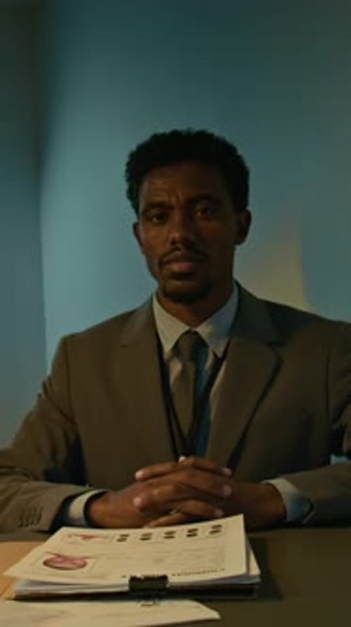 Man Sitting at Table with Documents and Serious Expression