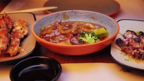 Una colorida selección de platos asiáticos: pollo teriyaki con verduras, calamares a la parrilla y pequeños