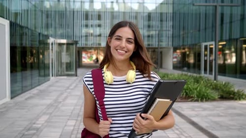 Portrait of Student Girl with Folder in a Campus Looking at Camera Smiling Happy Student