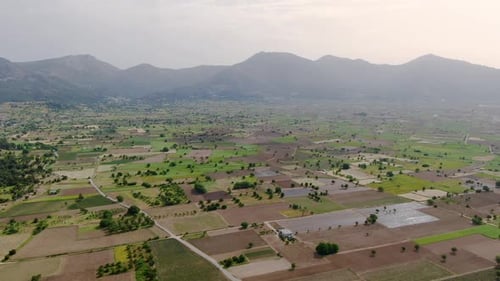 Aerial over beautiful clean green valley surrounded by tall dense mountains.