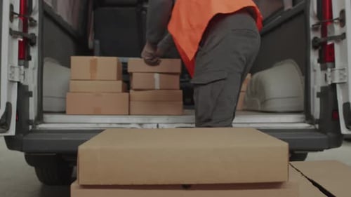 Delivery Worker Unloads Cardboard Packages from Delivery Van