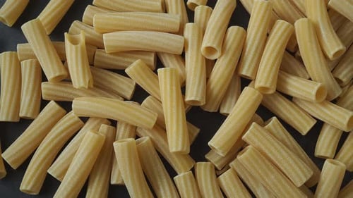 Rohe italienische Penne Rigate Pasta isoliert auf schwarzem Hintergrund