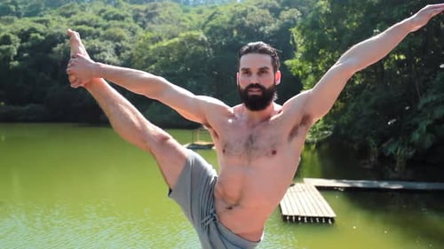 Hübscher, athletisch fitter Mann trainiert Yoga-Pose, steht auf einem Bein, streckt den Körper und arbeitet im Gleichgewicht