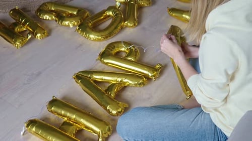 Woman Arranging Golden Party Balloons at Home