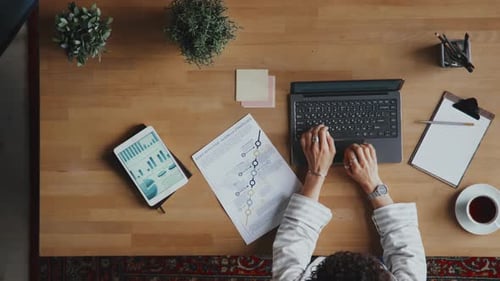 Person Works at Desk with Tablet and Data