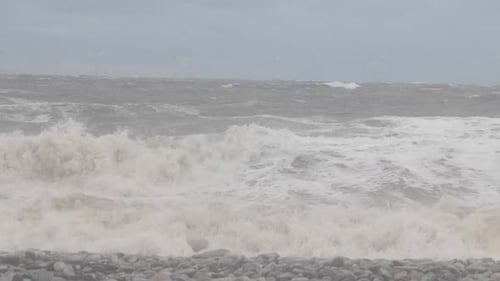 Dangerous stormy rolling coastal ocean waves foam blowing in rough windy weather