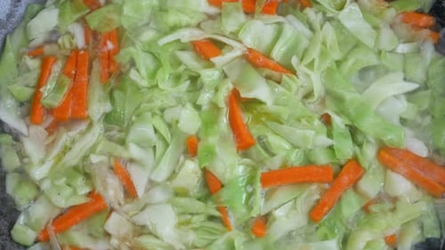 Fresh green cabbage is fried in a pan using hot cooking oil. Mix with carrot and chilli. Traditional