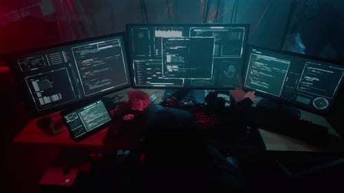 Hacker sitzt am Stuhl und tippt Informationen auf dem Computer