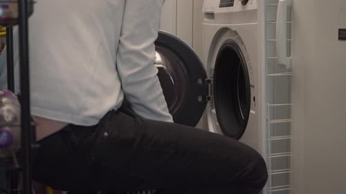 Adult Unloading Laundry From Washing Machine at Home