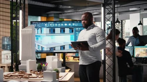 African American Real Estate Developer Reviews City Planning Layout on Laptop