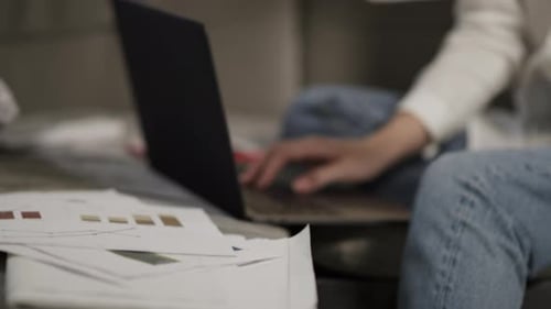 Tired business woman works late analyzing data on laptop at home on couch