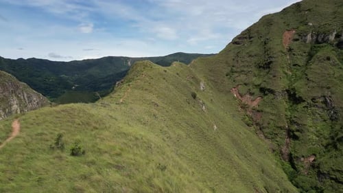 Mountain ridge aerial follows narrow hiking path on scenic summit crest
