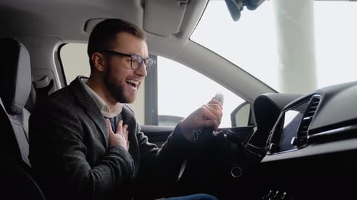 Happy Man Sits in New Electric Car in Shop Dealership and Celebrate Purchase of New Vehicle