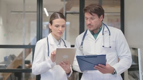 Doctors Collaborating with Tablet and Clipboard in Office